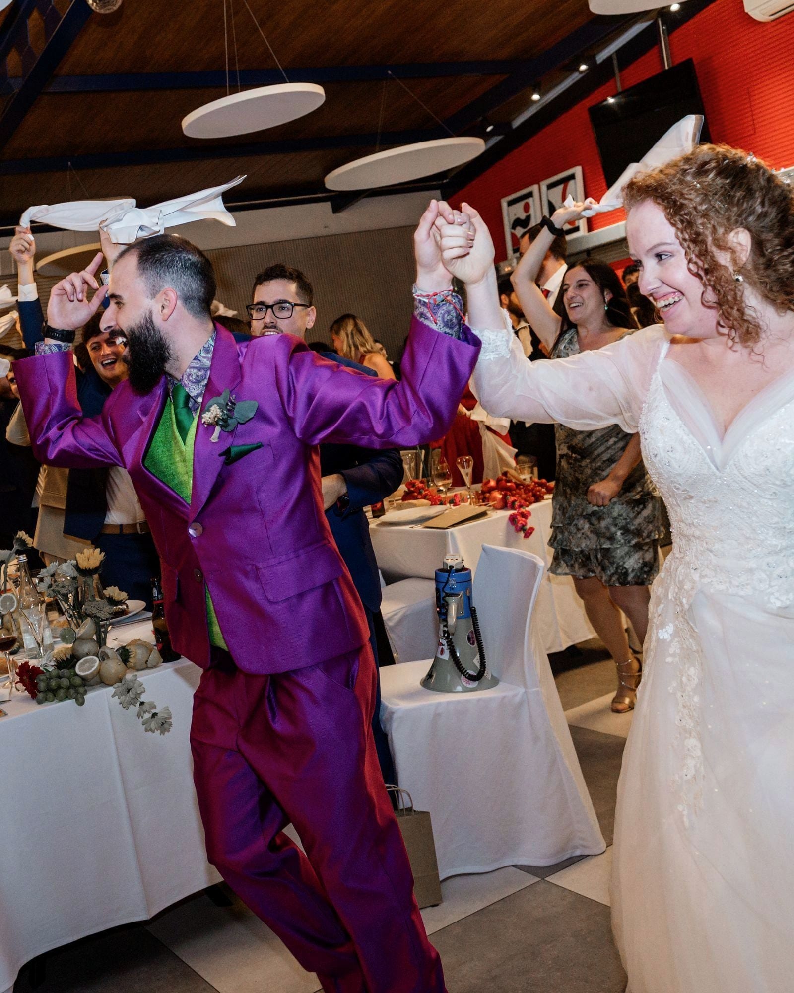 Los novios bailando entre las mesas mientras los invitados agitan servilletas