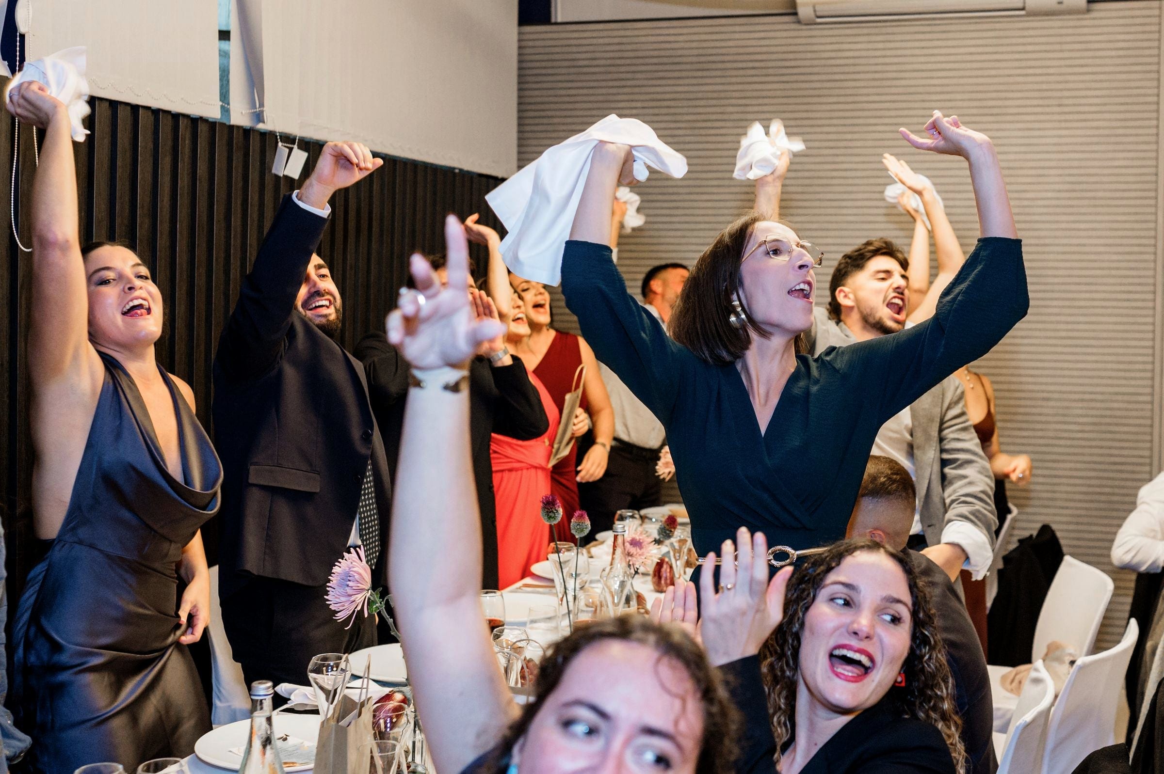 Invitadas celebrando con los brazos en alto en el banquete